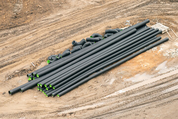 Pile of big plastic water pipes on a construction site background.