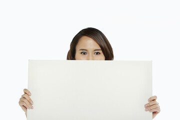 Woman holding up a blank placard, covering mouth