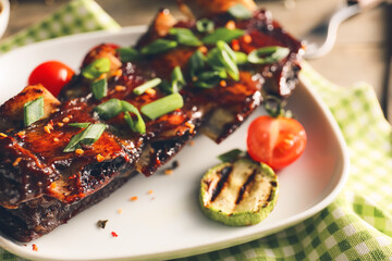 Tasty beef short ribs with vegetables on plate, closeup