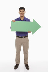 Businessman holding up a green arrow, pointing to the left