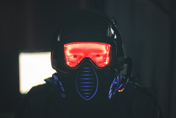 A man in goggles and gas mask on a computer screen background in a dark room.