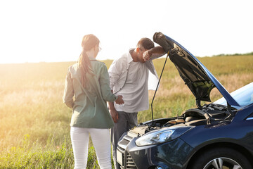 Young couple near broken car on road