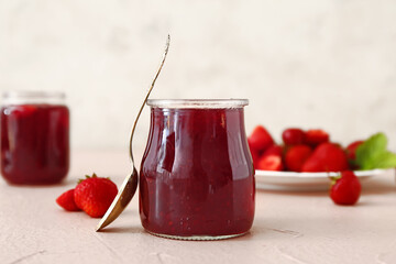 Jar of tasty strawberry jam on table