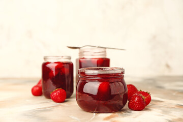 Jars of tasty strawberry jam on table