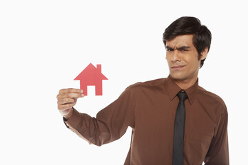 Fototapeta na wymiar Businessman holding up a cut out house