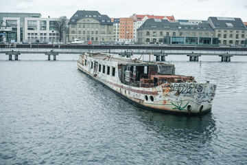 Fototapeta na wymiar Berlino aspetta la tempesta. Veduta sul fiume con barca abbandonata.