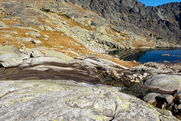 Fototapeta na wymiar Lake in mountains. Pond in Valley of Five Spis Lakes surrounded by rocky summits, High Tatra Mountains, Slovakia.