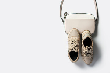 Women's beige sneakers and cross-body bag on a light background. Flat lay, top view