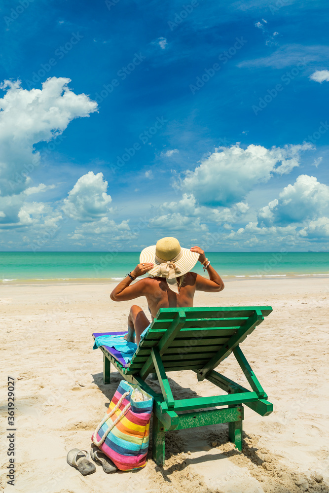 Wall mural Woman on a sun lounger at the white sand tropical beach