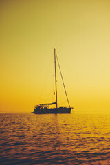 Silhouette of a sailing boat in sunset / sunrise time and ocean horizon.