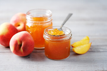 Peach jam in glass jar. Close-up view. Gray background