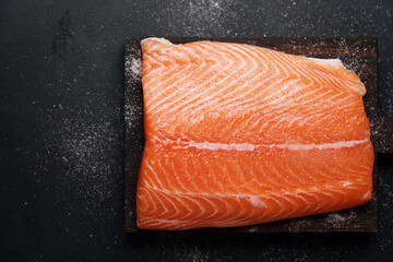 Salted salmon filet on black background. Close-up view of raw fish