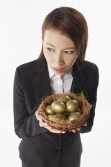 Businesswoman carrying a nest filled with gold eggs