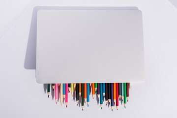 top view of colored pencils in modern laptop on white background
