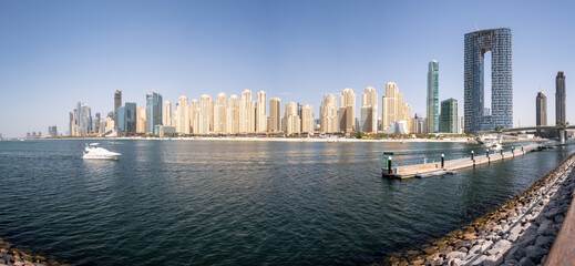 Naklejka premium Dubai, UAE. Panoramic landscape view of Jumeirah Beach Residence (JBR), The Address Residences Jumeirah Resort beachfront skyline and bay seen from Bluewaters Island, sunny day.