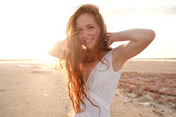 Beautiful young lady with long healthy red hair and cute dress