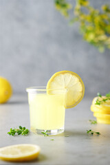Glass of limoncello traditional Italian alcoholic drink decorated with thyme. Light gray...