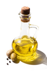 olive oil in jar near green olives and black pepper on white background
