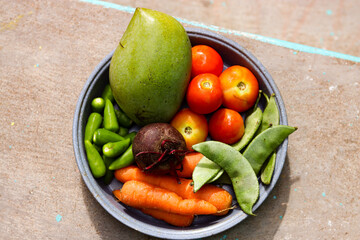 fresh vegetables on a plate mango,beet root,carrot,broad beans,tomato,green chili