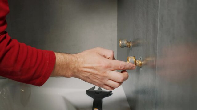 Men's hand causes the paste to seal threaded connections. Install the faucet in the bathroom.