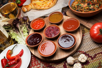 spicy sauces in round plates. cheese and vegetables around. close-up, top view. Georgian national cuisine