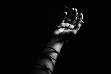 Concept photo of a hand and arm tied with barbed wire artistic conversion