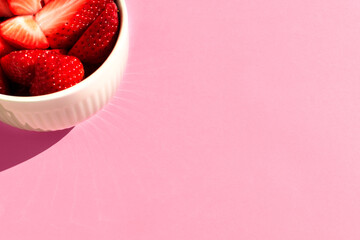 Strawberry in bowl on pink background.