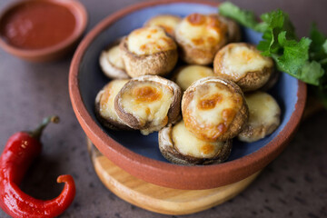 Baked juicy mushrooms with suluguni in a plate close-up. Georgian cuisine