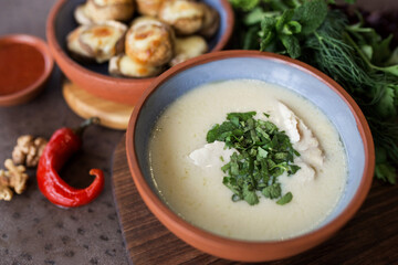 Cream soup with meat and parsley. Plate with baked mushrooms. Chili pepper and walnut. Georgian cuisine