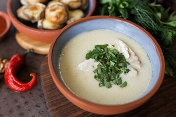 Cream soup with meat and parsley. Plate with baked mushrooms. Chili pepper and walnut. Georgian cuisine