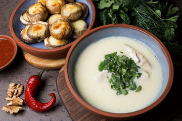 Cream soup with meat and parsley. Plate with baked mushrooms. Chili pepper and walnut. Georgian cuisine