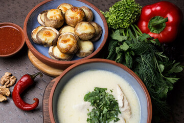 Cream soup with meat and parsley. Plate with baked mushrooms. Chili pepper and walnut. Georgian cuisine