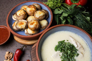 Cream soup with meat and parsley. Plate with baked mushrooms. Chili pepper and walnut. Georgian cuisine