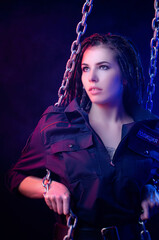 a girl in a police uniform with dreadlocks in neon light with chains and handcuffs English...