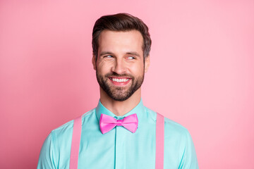 Photo of handsome guy trend clothes look side empty space know evil secret toothy smile cunning chatterbox person wear shirt suspenders bow tie isolated pastel pink color background