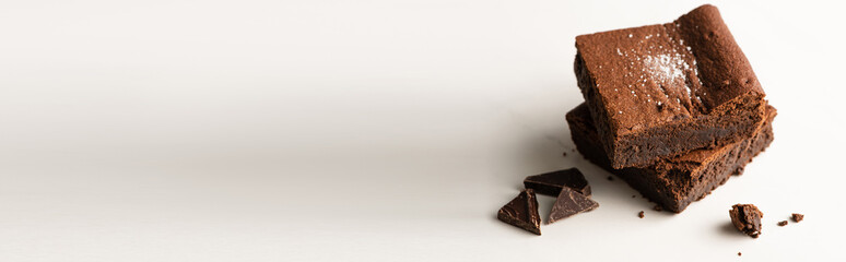 delicious brownie pieces with chocolate on white background, panoramic shot