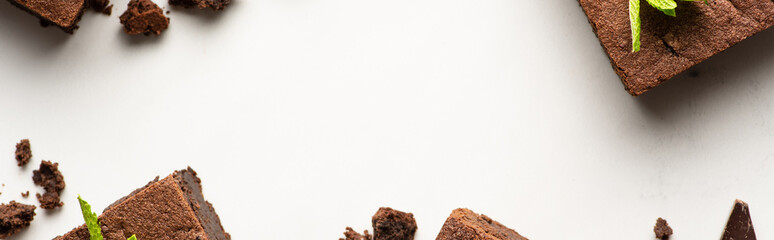 top view of delicious brownie pieces with mint on white background, panoramic shot