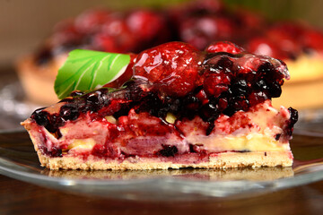 Piece of forest fruit red cake (pie) with gelatin garnished with green sugar leaves
