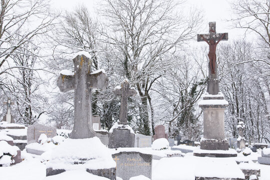 des tombes , des pierres tombales dans un cimeti&egrave;re chr&eacute;tien catholique en hiver sous la neige. Symbolique de la mort froide.