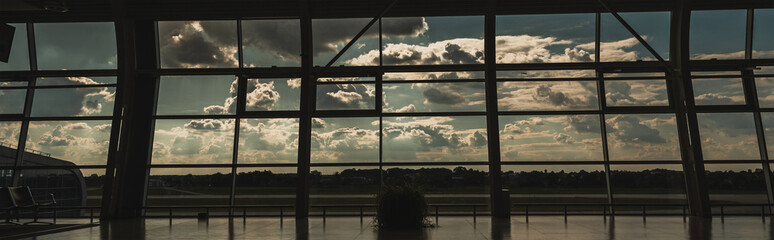 Panoramic orientation of windows in airport waiting hall with cloudy sky at background in Copenhagen, Denmark