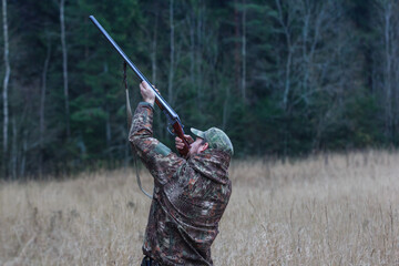 Hunter with a gun. Standing in the forest and waiting for prey