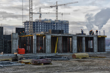 the grouping of workers are working on construction site, tower cranes