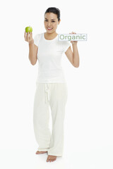 Fototapeta na wymiar Cheerful woman with a green apple and an Organic placard