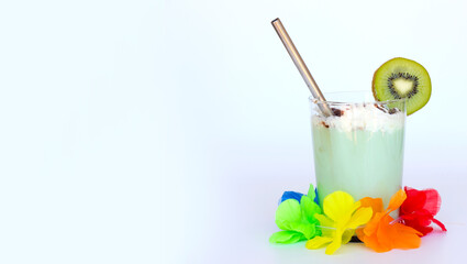 Tropical caribbean exotic green cocktail with slice of kiwi in a glass with metal cocktail tube and hawaiian flower garland isolated on white. Space for text. Milkshakes and smoothie
