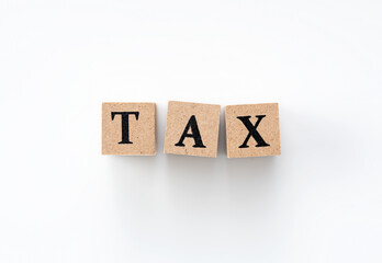 A wooden block with the word TAX written on it on a white background