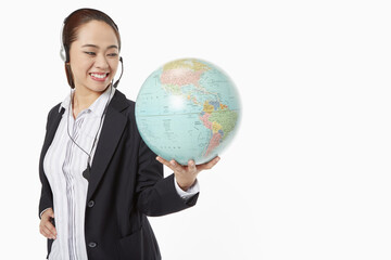 Fototapeta premium Businesswoman with headset holding a globe