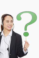 Businesswoman with headset holding up a question mark symbol