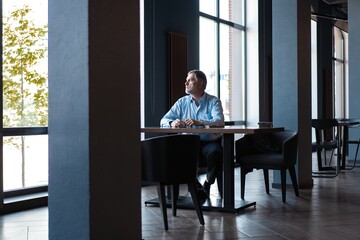 Pensive businessman drinking coffee in cafe and looking away.