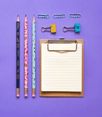 School flatlay voilet background. School supplies. Notebook, markers, 
paper clips, pen, clamp, phone. School banner 2020. Back to school. Top view. 