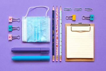 School supplies flatlay voilet background. Notebook, markers, 
paper clips, pen, clamp, phone,  face mask. School banner 2020. Online education. Back to school. Top view. Virus situation education 